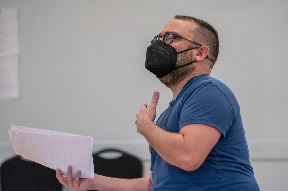 Stephen Brackett in rehearsal holding a script and gesturing